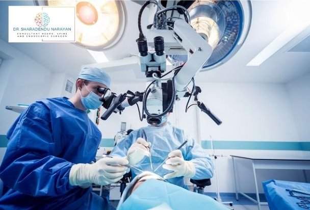 Surgeon using a surgical microscope during a procedure in an operating room, with another medical professional assisting