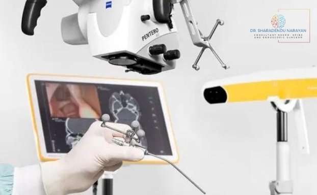 Close-up image of a surgeon's hand manipulating a precise surgical instrument under a microscope with a display screen showing brain scans in the background